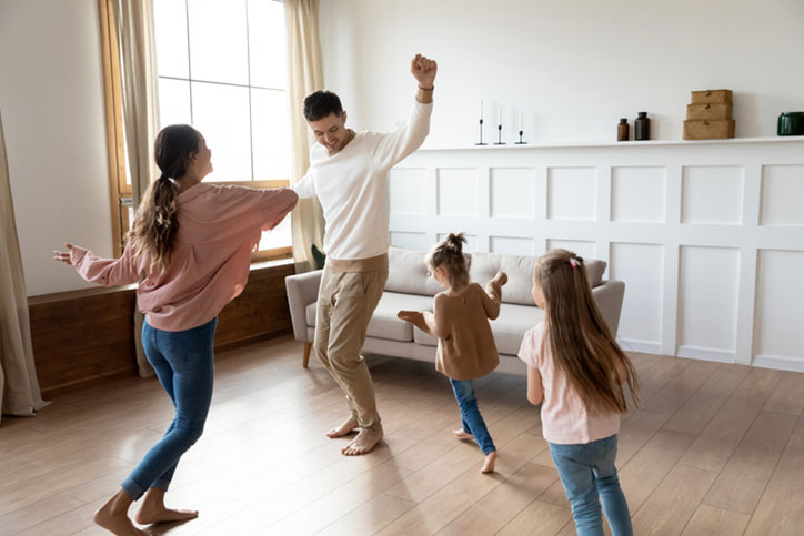 Young family dancing around the living room
